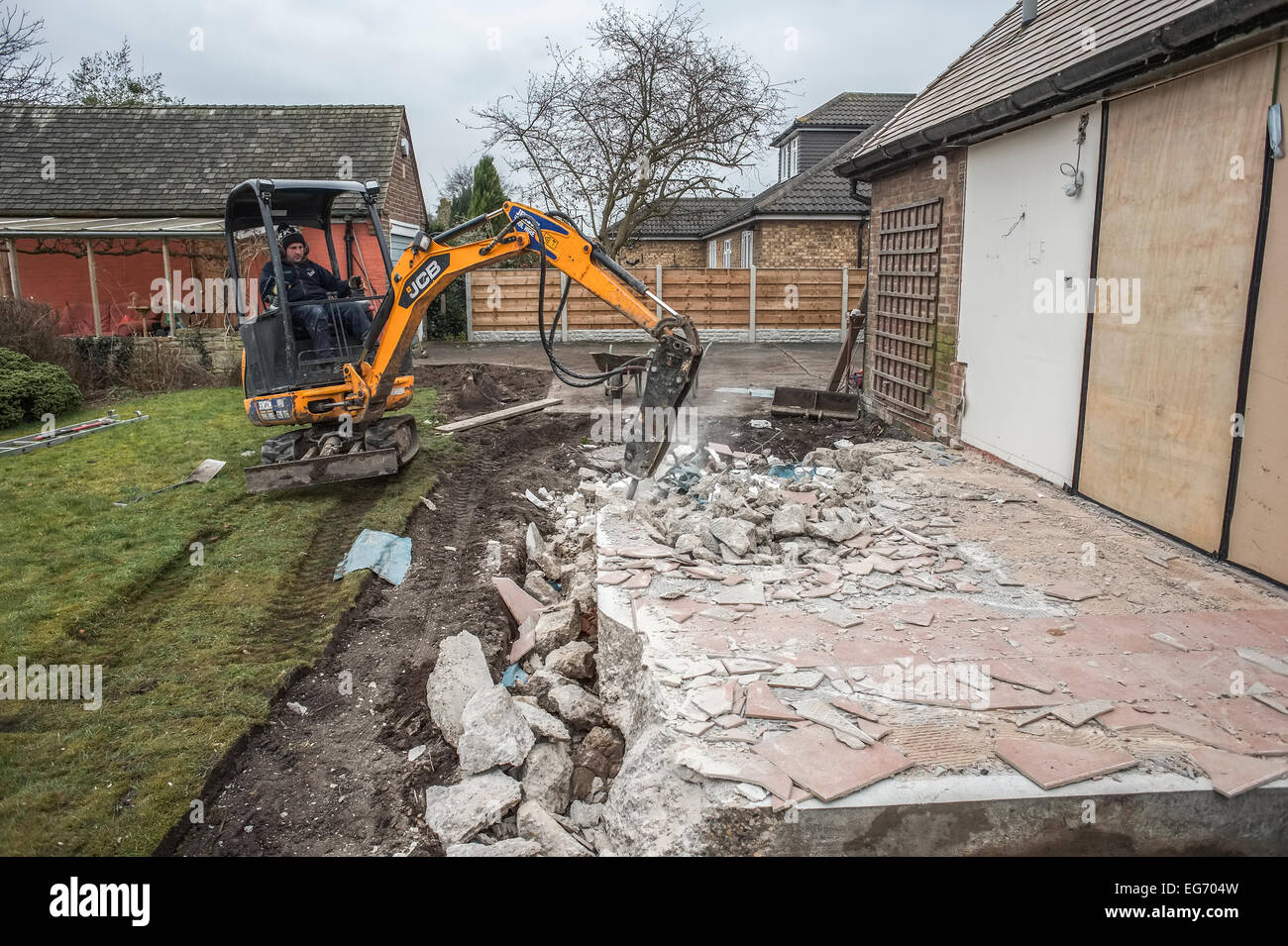 Ausgraben alten Grundlagen Fundamenten auf ein Wohn-Erweiterungsprojekt mit ein Schwanz an einem Kompaktbagger befestigt. Stockfoto