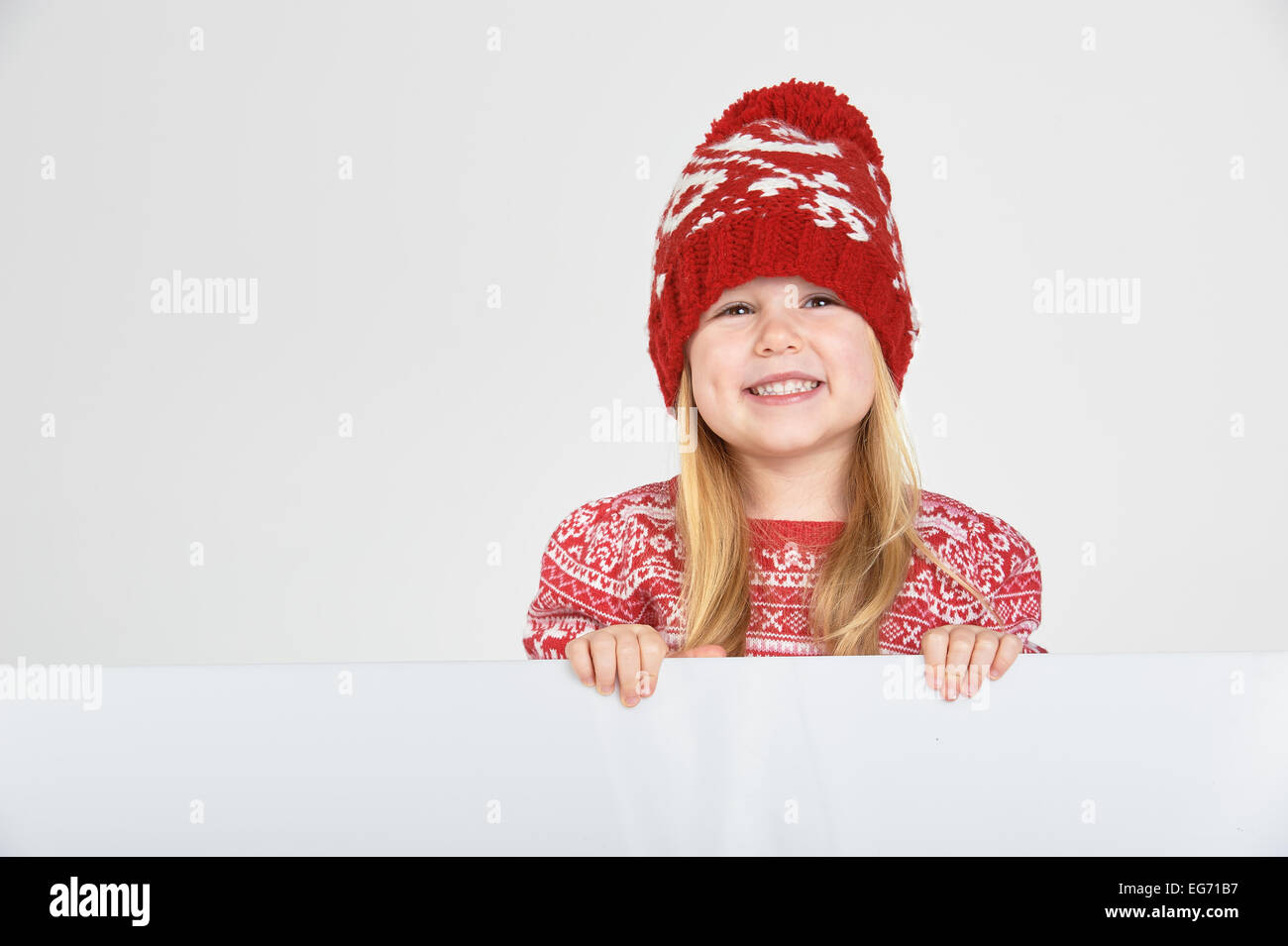 Schöne blondes Mädchen in einem roten Wintermütze und Pullover mit Leerraum für Text oder Werbung lächelnd Stockfoto