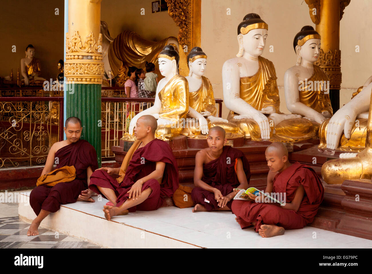 Vier Mönche sitzen unter vier Buddha-Statuen, Shwedagon-Pagode, Yangon, Myanmar (Burma), Asien Stockfoto