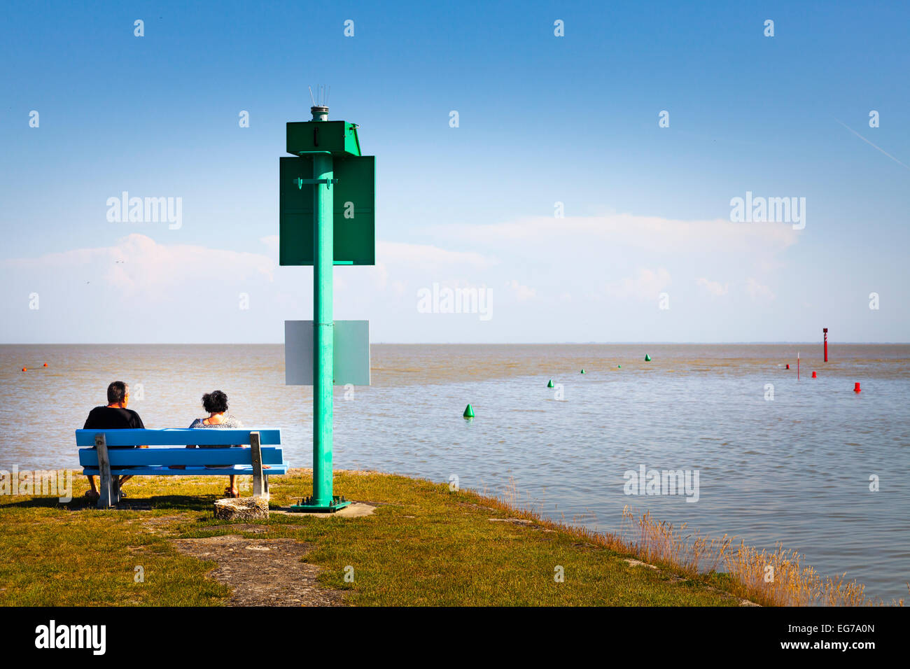 Paar auf Bank Blick auf das Meer mit Kanal und Hafen Eingang Marker Stockfoto