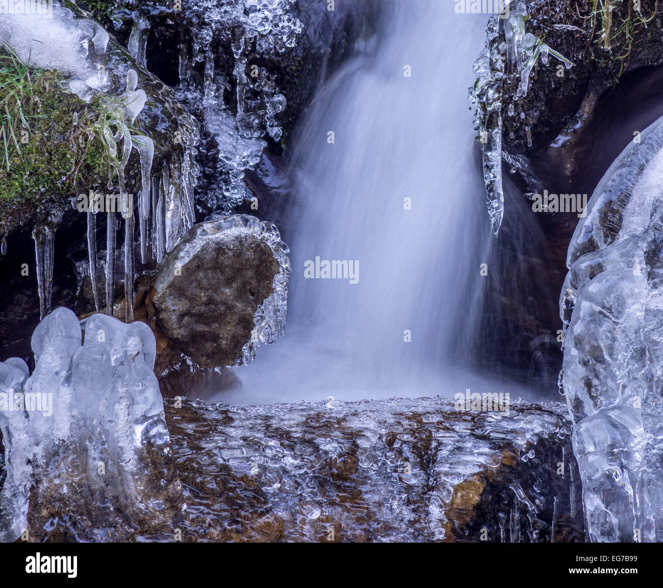 Eiszapfen auf Felsbrocken und fließendes Wasser Stockfoto