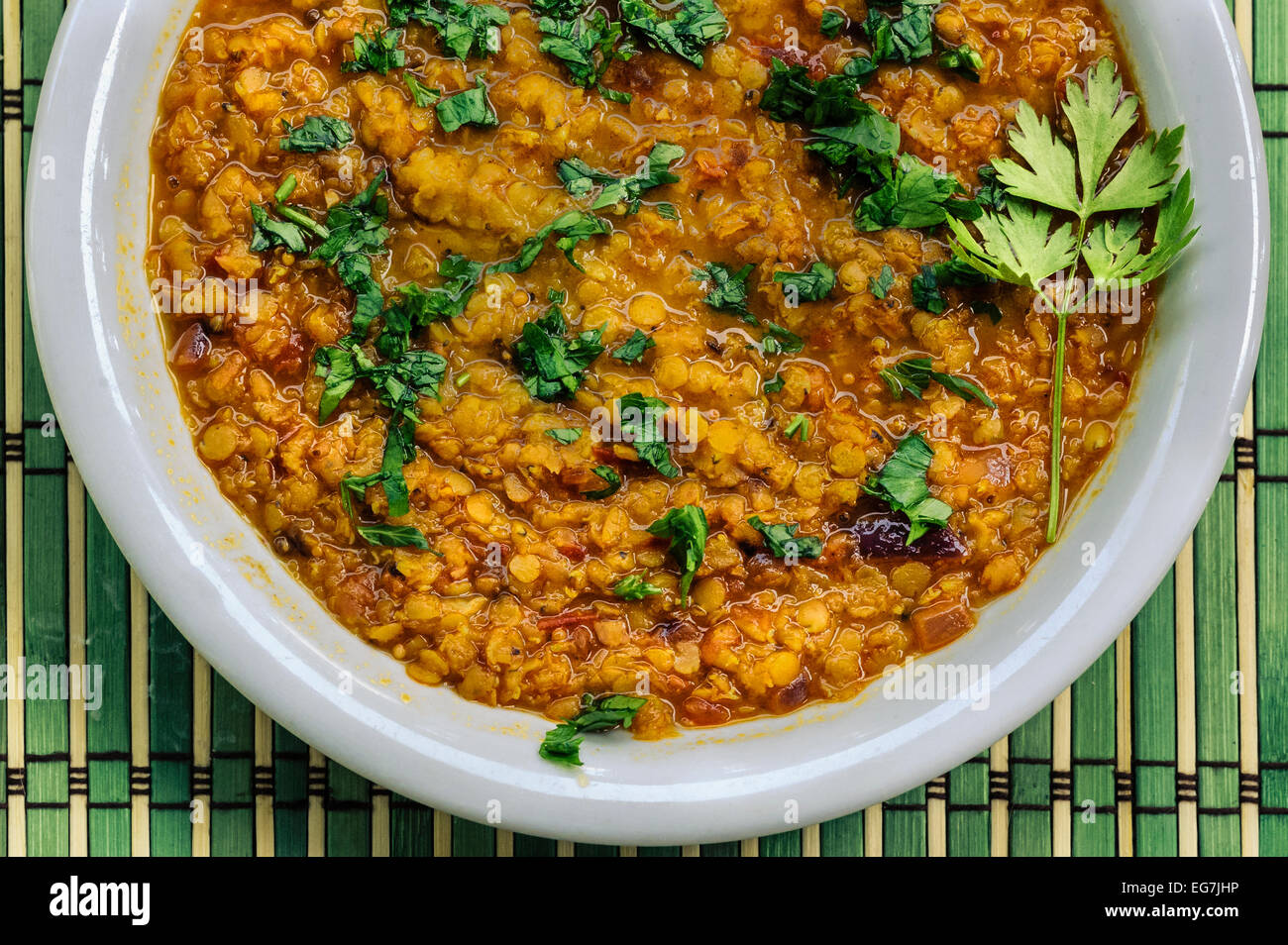 Nahaufnahme von einem hausgemachten vegane Linsensuppe Eintopf in einem weißen Teller mit grünem Bambus Hintergrund Stockfoto