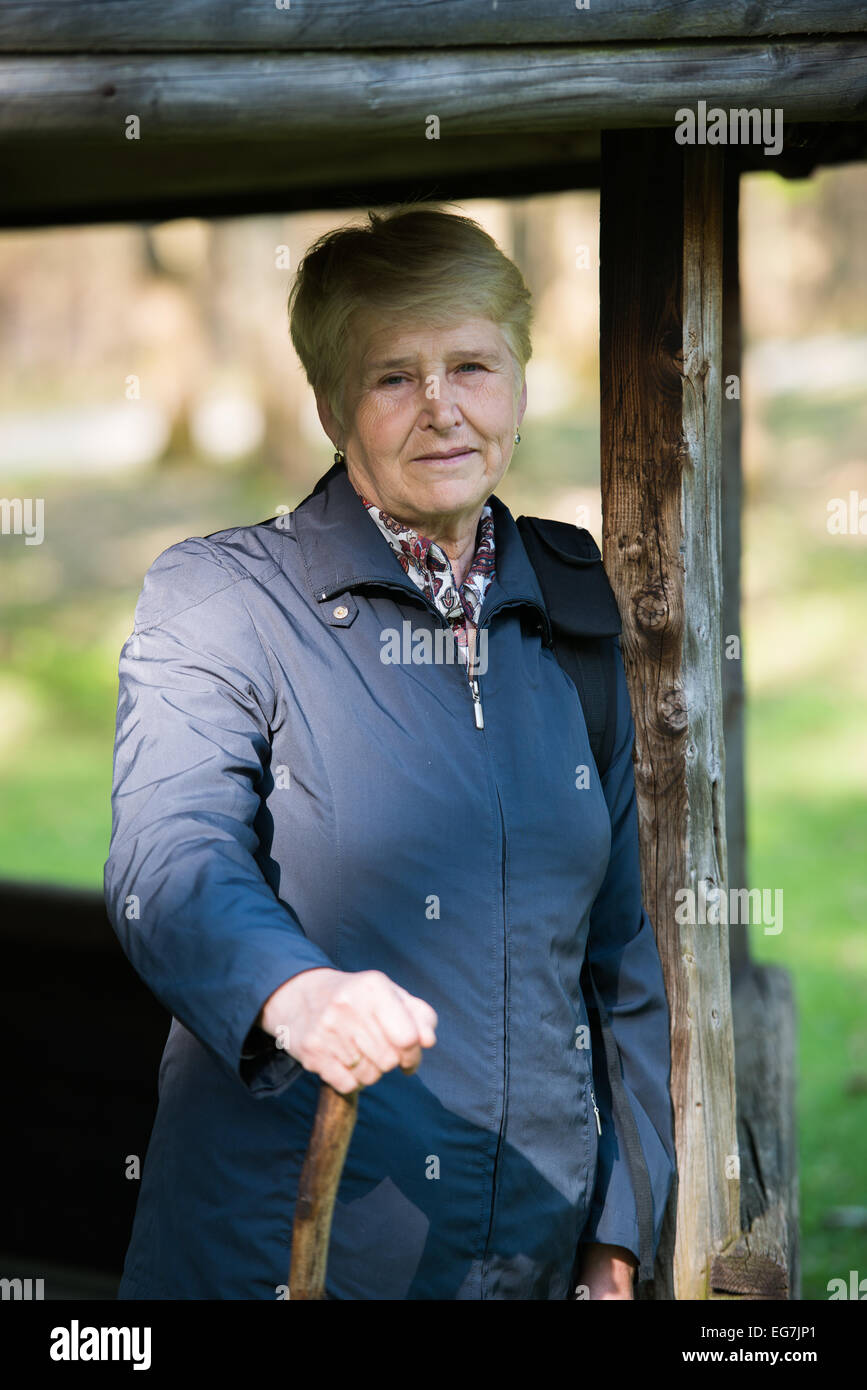 Ältere Frau, die in der Nähe der Laube im Wald und Entspannen Stockfoto