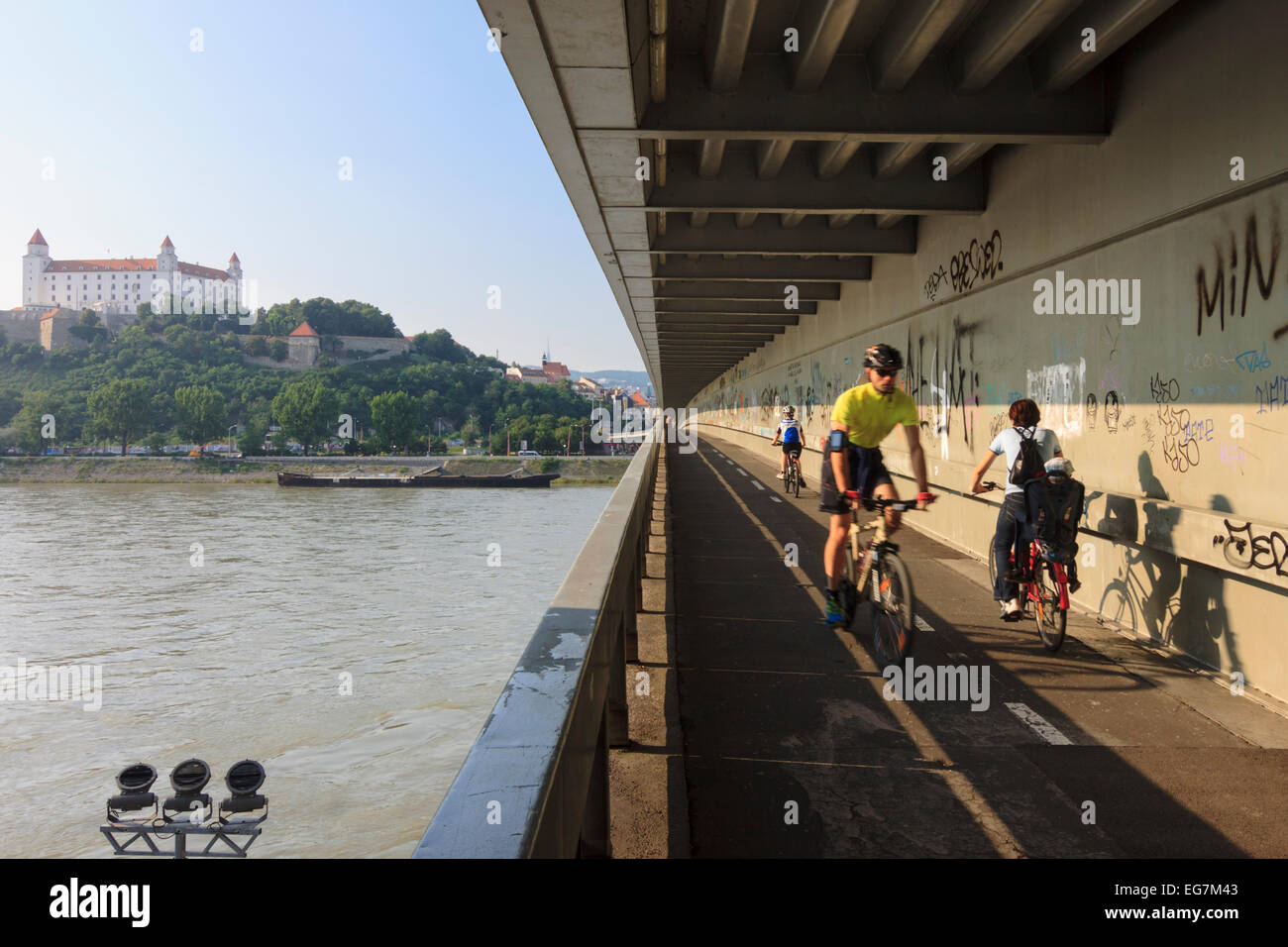 Radfahrer auf der neuen Brücke mit Schloss im Hintergrund, Bratislava, Slowakei Stockfoto