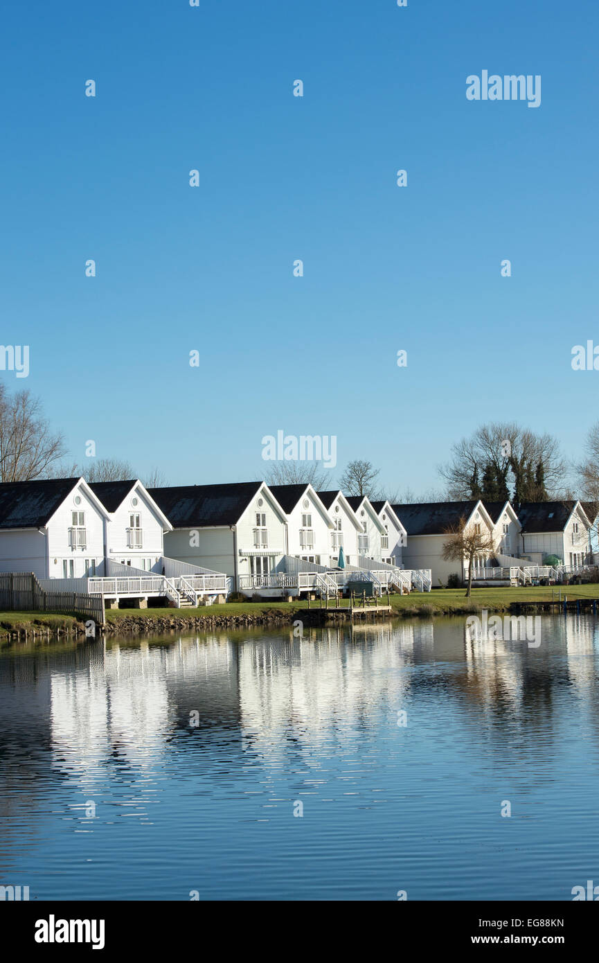 Filmklappe Stil Häuser entlang eines Sees im Wasserzeichen Club, Cotswold Water Park, Gloucestershire, England Stockfoto Filmklappe Stil Häuser entlang eines Sees im Wasserzeichen Club, Cotswold Water Park, Gloucestershire, England Stockfoto