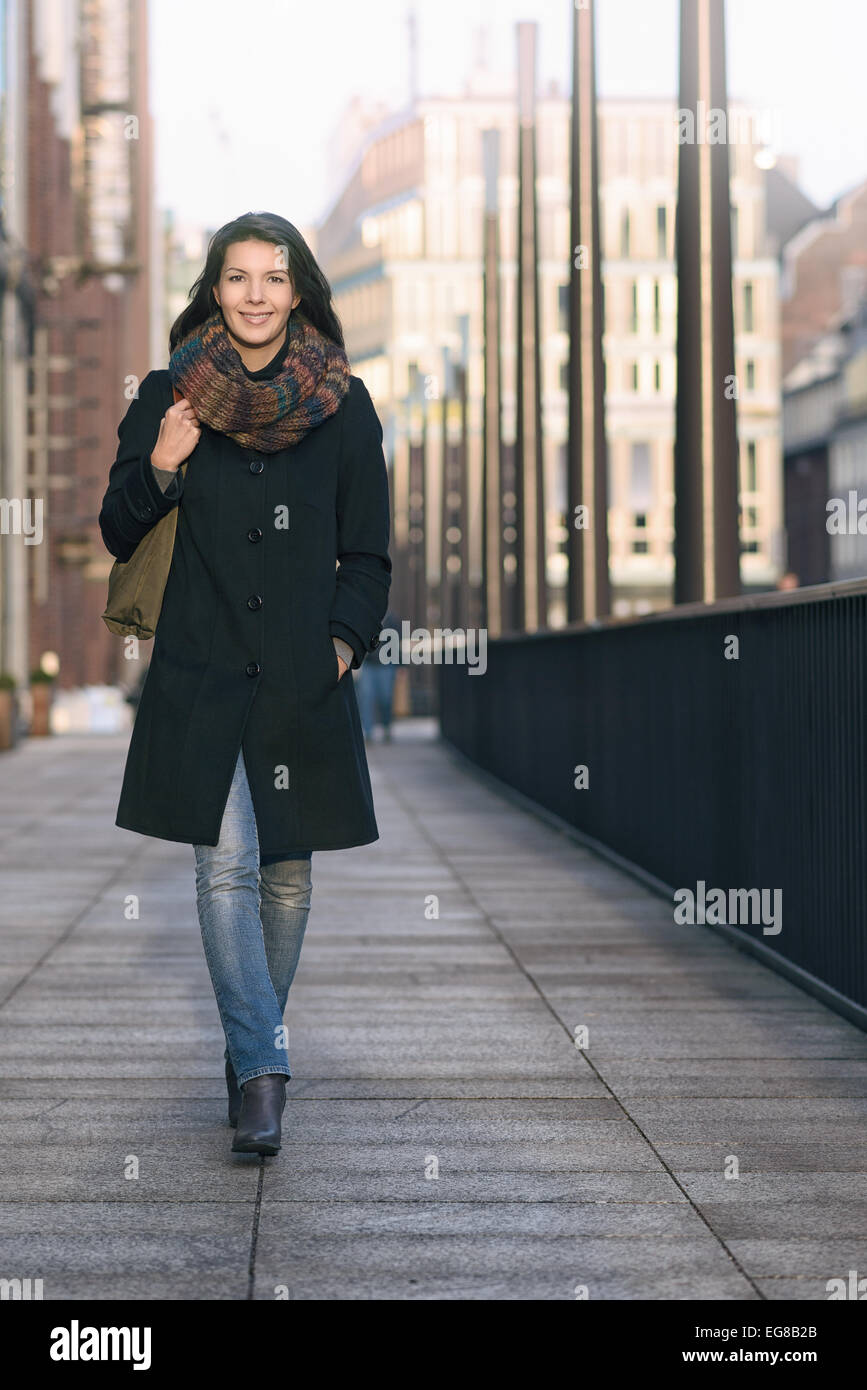 Volle Länge Schuss von stilvolle Pretty Young Woman im Herbst Mode zu Fuß die Stadt in die Kamera schaut. Stockfoto