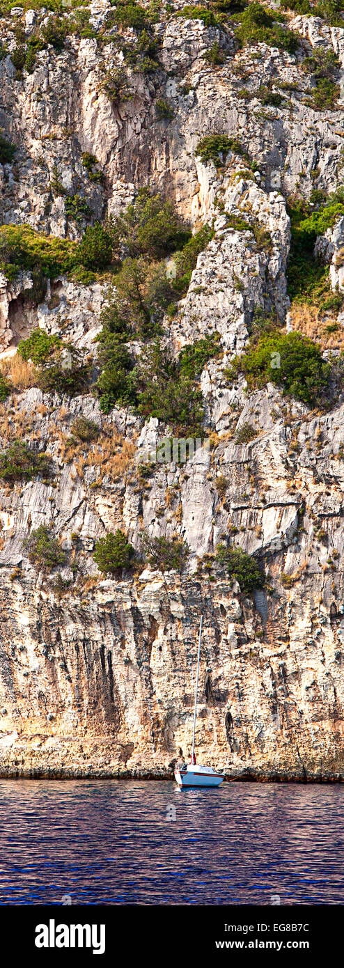 Kroatien, die offene Meer Küste von Ciovo Insel präsentieren einen sehr hohen Bekanntheitsgrad der Felsen gemacht. Das Segelboot sieht sehr klein im Vergleich Stockfoto