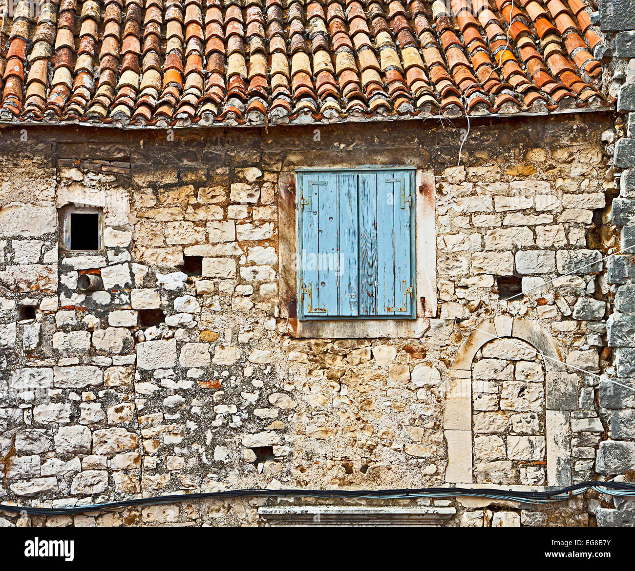 Fassade des alten dalmatinischen Haus aus Mörtel und Stein-Blöcke mit gekrümmten roten gefliest Dach und Fenster mit hölzernen Jalousien geschlossen Stockfoto