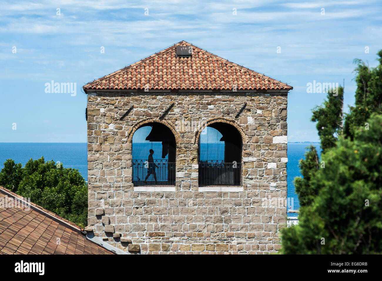 Triest, Italien - ein Mann geht die Glocke Turm von San Giusto Kathedrale an einem schönen sonnigen Tag.  Golf im Hintergrund. Stockfoto