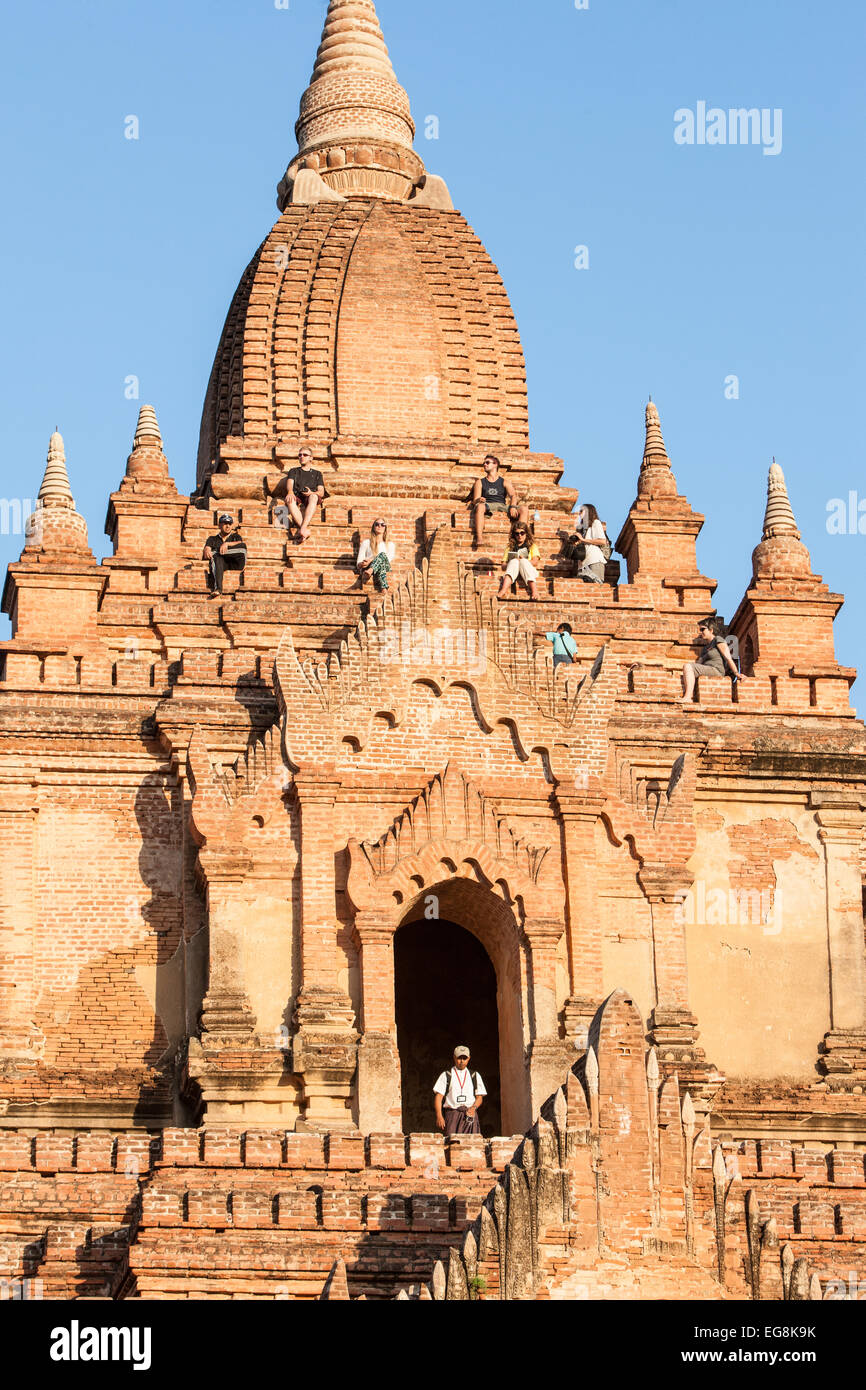 Touristen sitzen auf North Guni buddhistischer Tempel, eine beliebte Tempel zu Sonnenuntergang über Ebenen Pagan, Bagan Burma, Myanmar Stockfoto