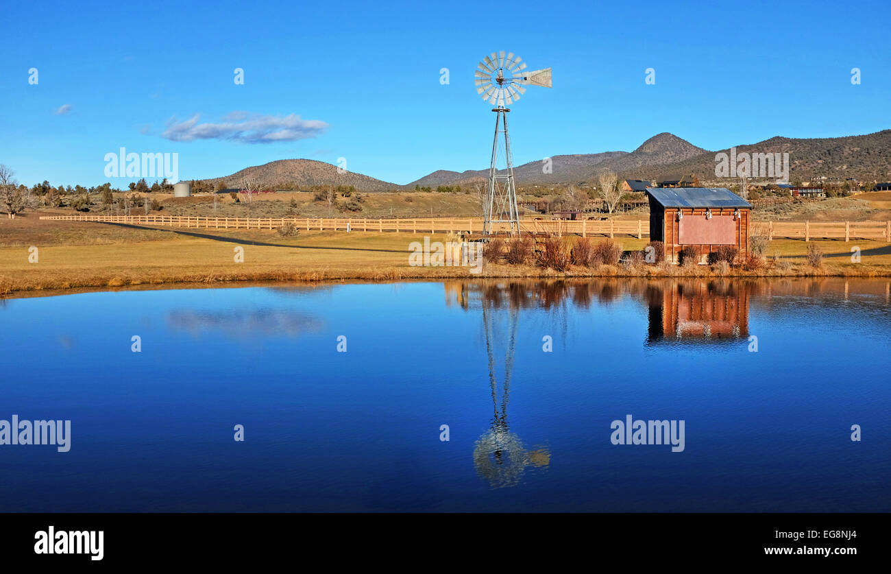 Eine Ranch Windmühle spiegelt sich in einer Ranch Teich während einem Wintertag auf der Brasada Ranch in Zentral-oregon Stockfoto