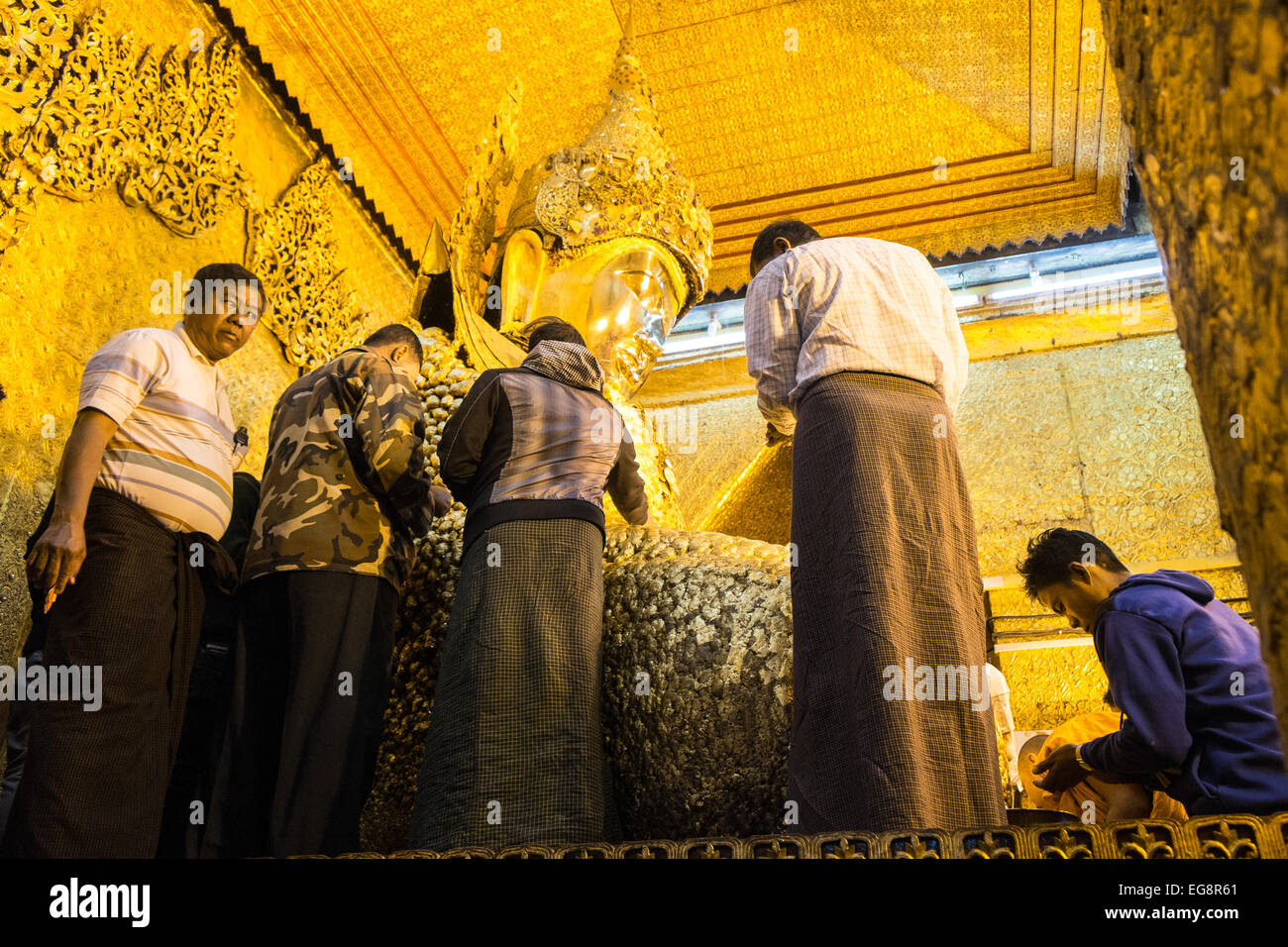 Anwenden von Blattgold auf riesigen goldenen Buddha, Mahamuni-Statue eines der am meisten verehrten Buddhas in Burma.Mandalay, Burma, Myanmar. Stockfoto