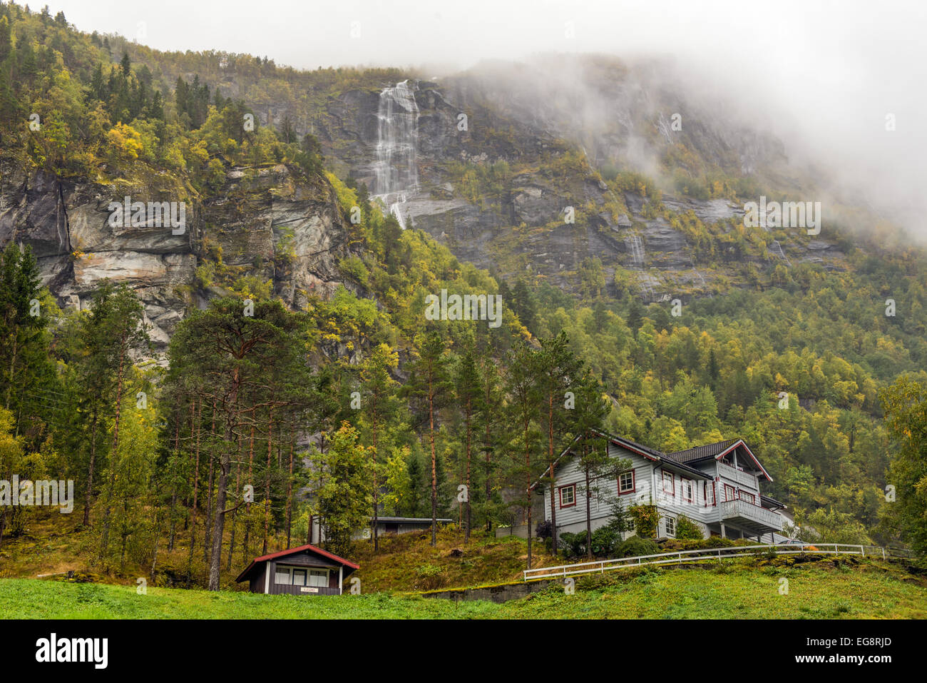 Typische norwegische Holzhaus mit Wasserfall im Nebel Stockfoto