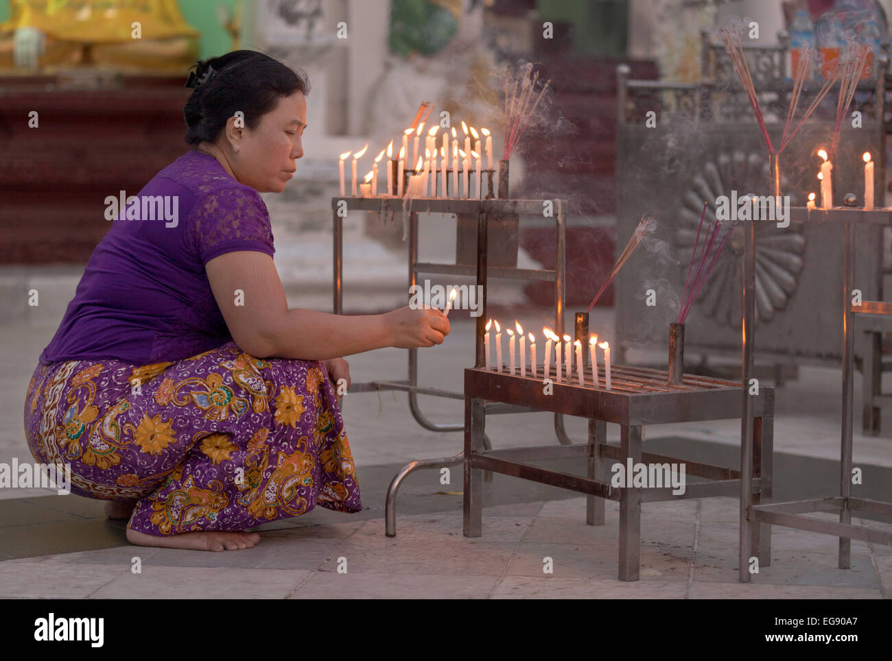 Applying burmesischen Frau Anzünden einer Kerze bei Sonnenuntergang an der Shwedagon-Pagode, Yangon Myanmar (Burma), Asien Stockfoto