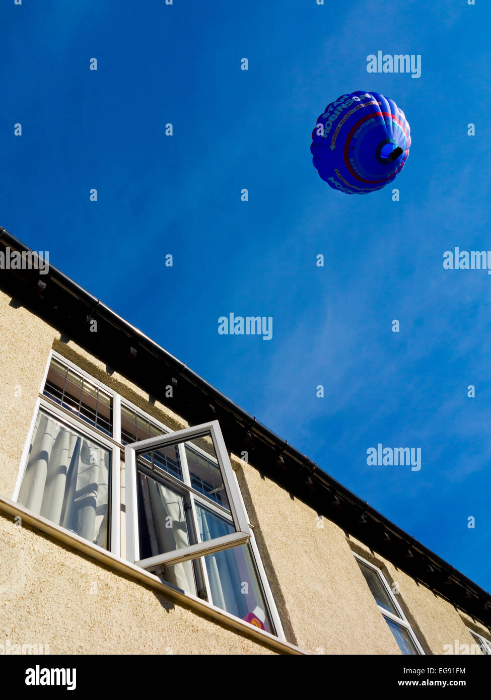 Blaue Heißluftballon mit Werbung für Stan Robinson Express Paletten bundesweit vor einem strahlend blauen Himmel in Derbyshire UK Stockfoto