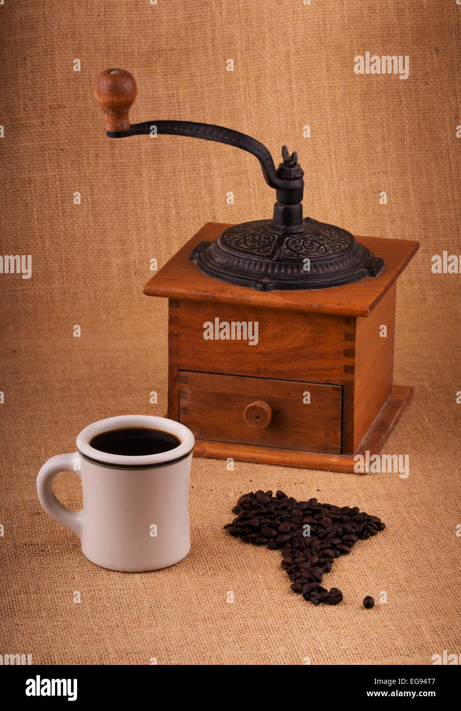 Tasse Kaffee und Bohnen in Form von Südamerika, mit einer Mühle auf Hintergrund, mit leichten vignette Stockfoto