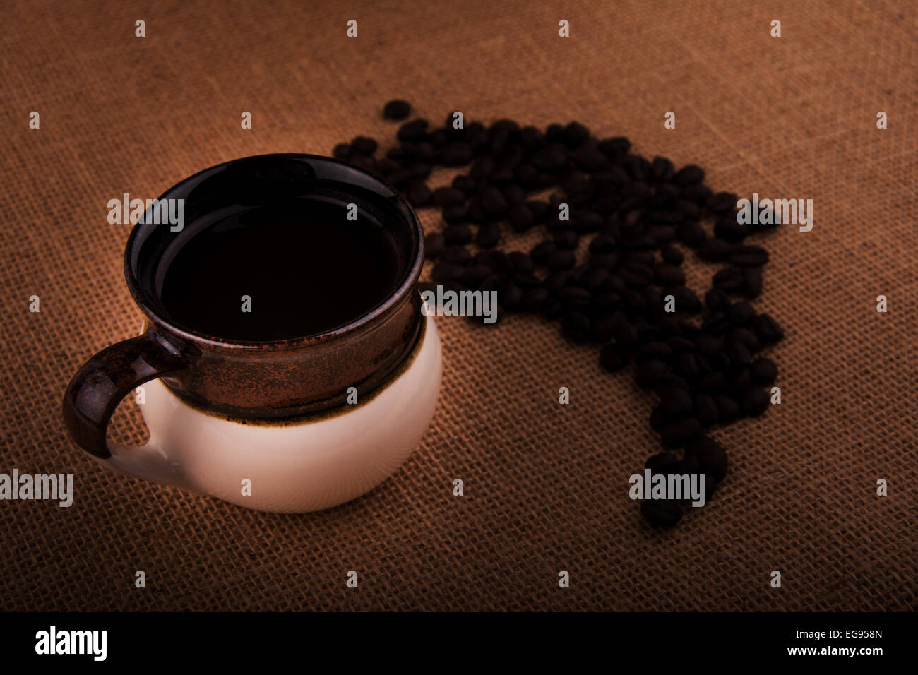 Tasse Kaffee mit Kaffeebohnen in einem Leinensack, warm getönten Bild mit vignette Stockfoto
