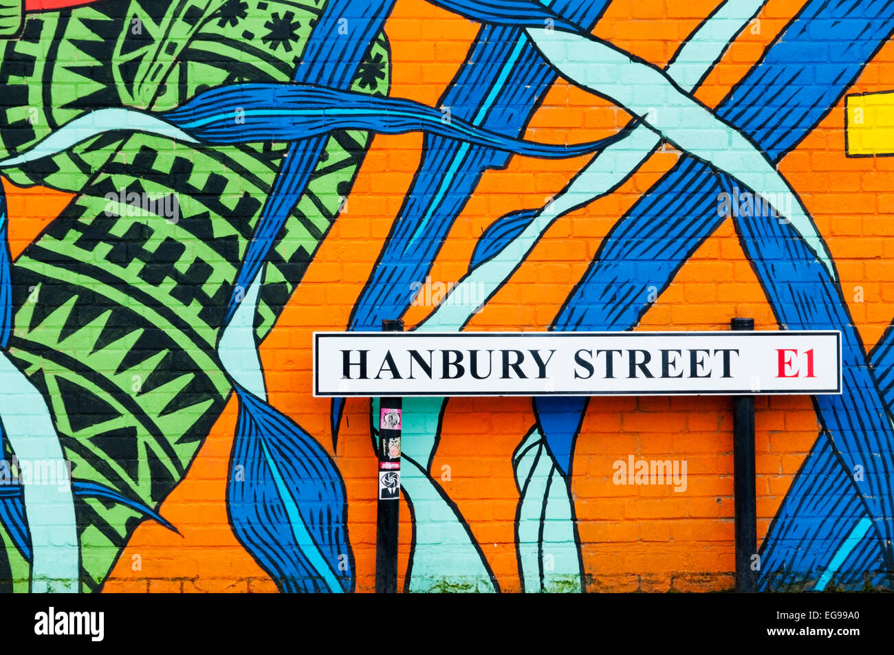 Straßenschild für Hanbury Street, Whitechapel & Wand dekoriert mit bunten Graffiti von der brasilianischen Gruppe Bicicleta Sem Freio Stockfoto
