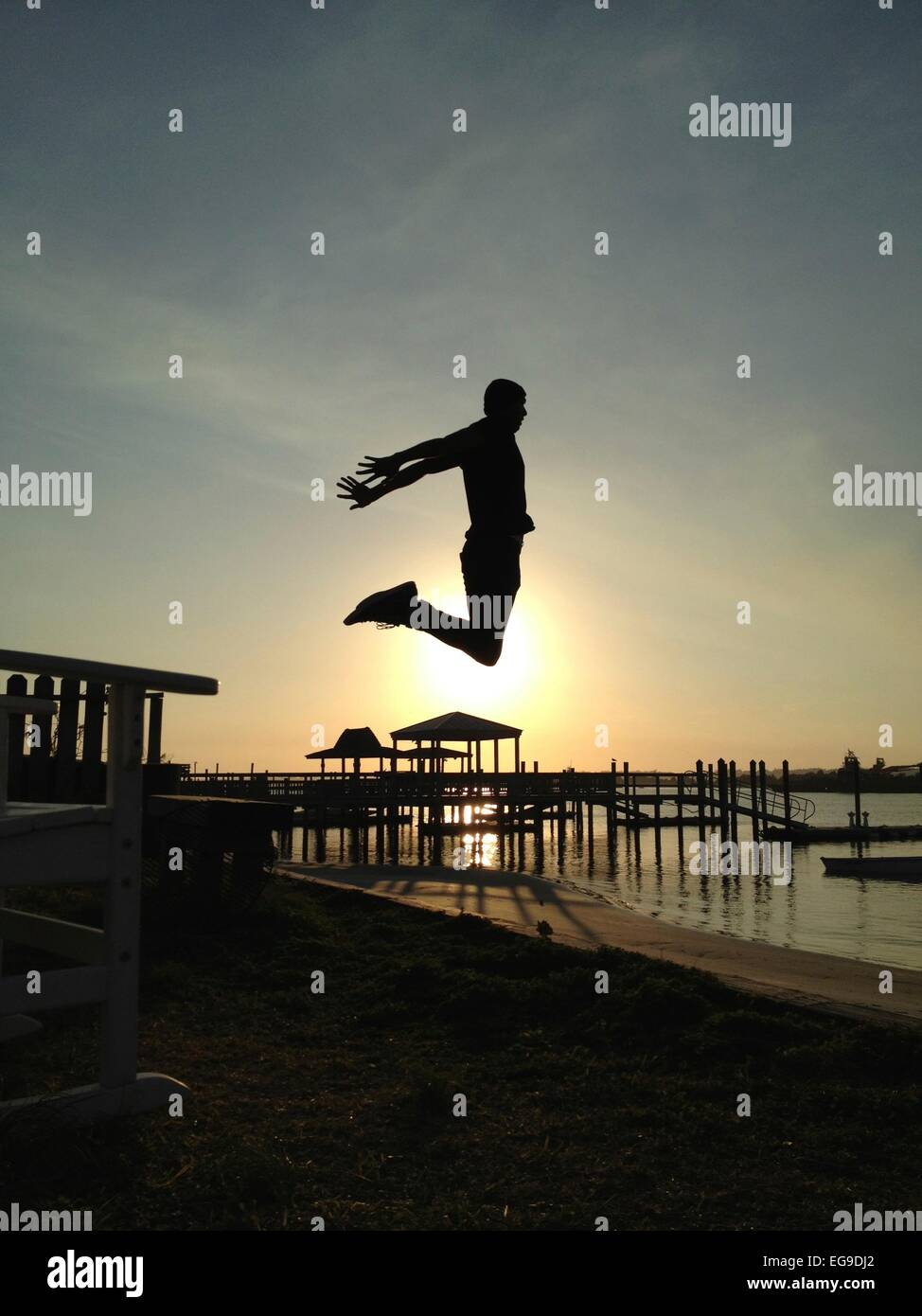 Mann springt hoch in Sonnenuntergang am Strand Stockfoto
