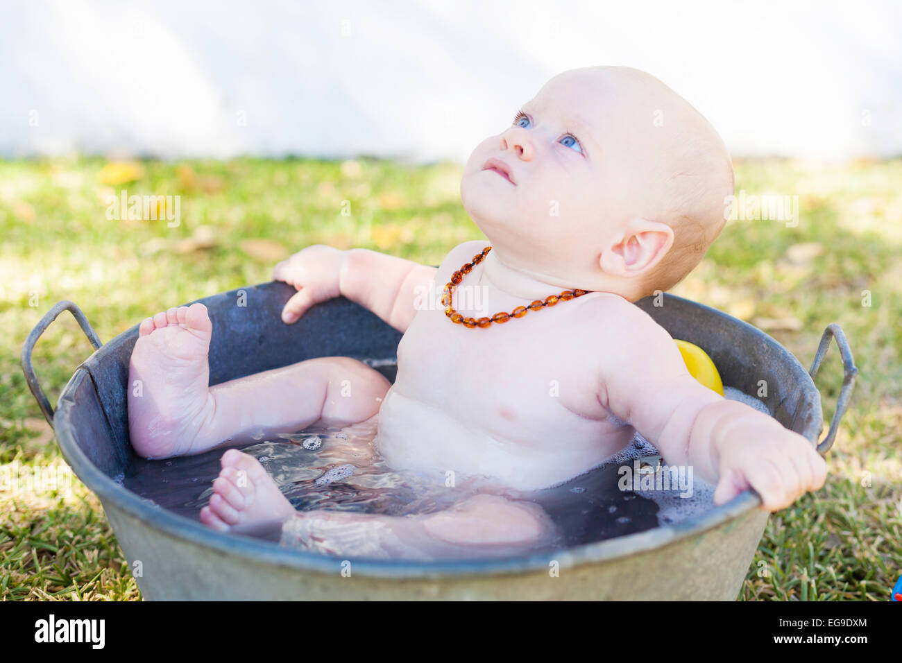 Baby Junge sitzt in einem Eimer mit Wasser Stockfoto