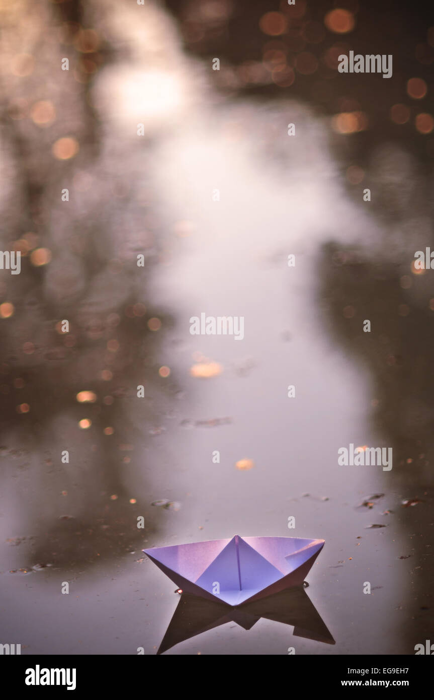 Papierboot schwimmt auf dem Wasser von einem Brunnen mit goldenen bokeh Stockfoto