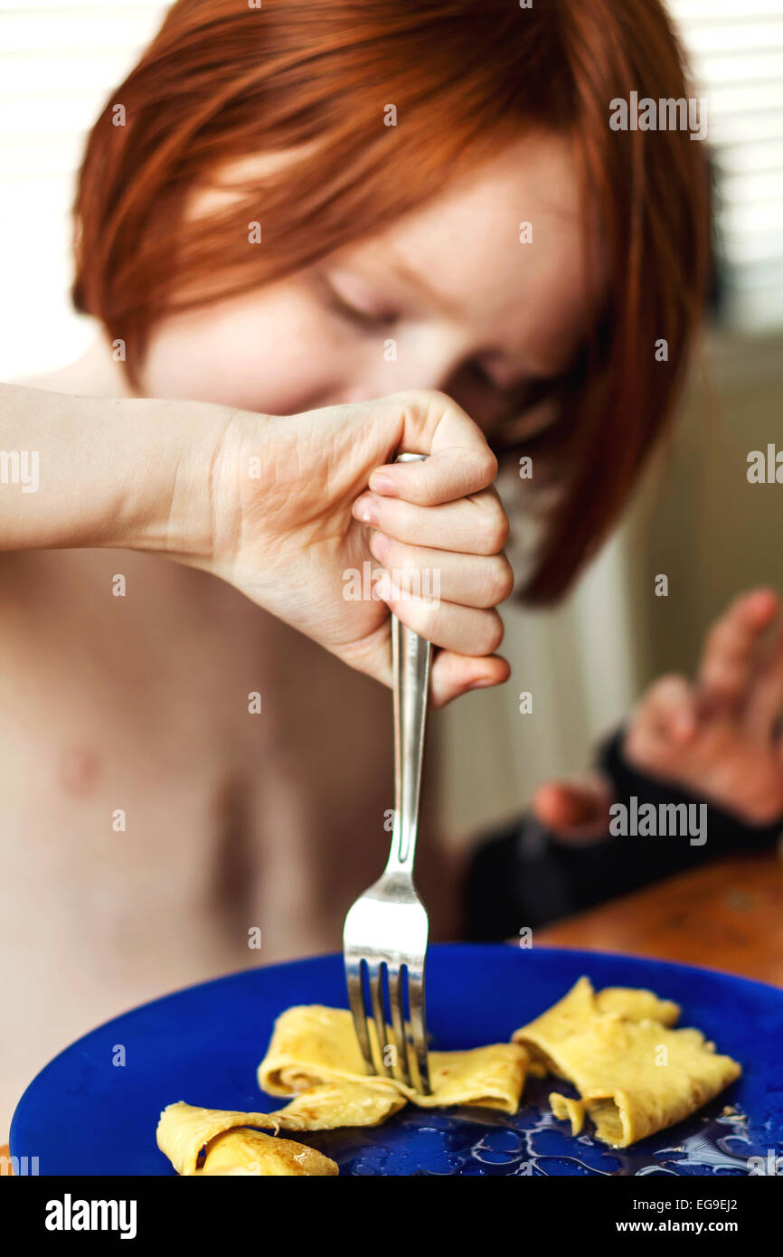 Junge mit einem gebrochenen Arm Essen Pancake-Frühstück Stockfoto