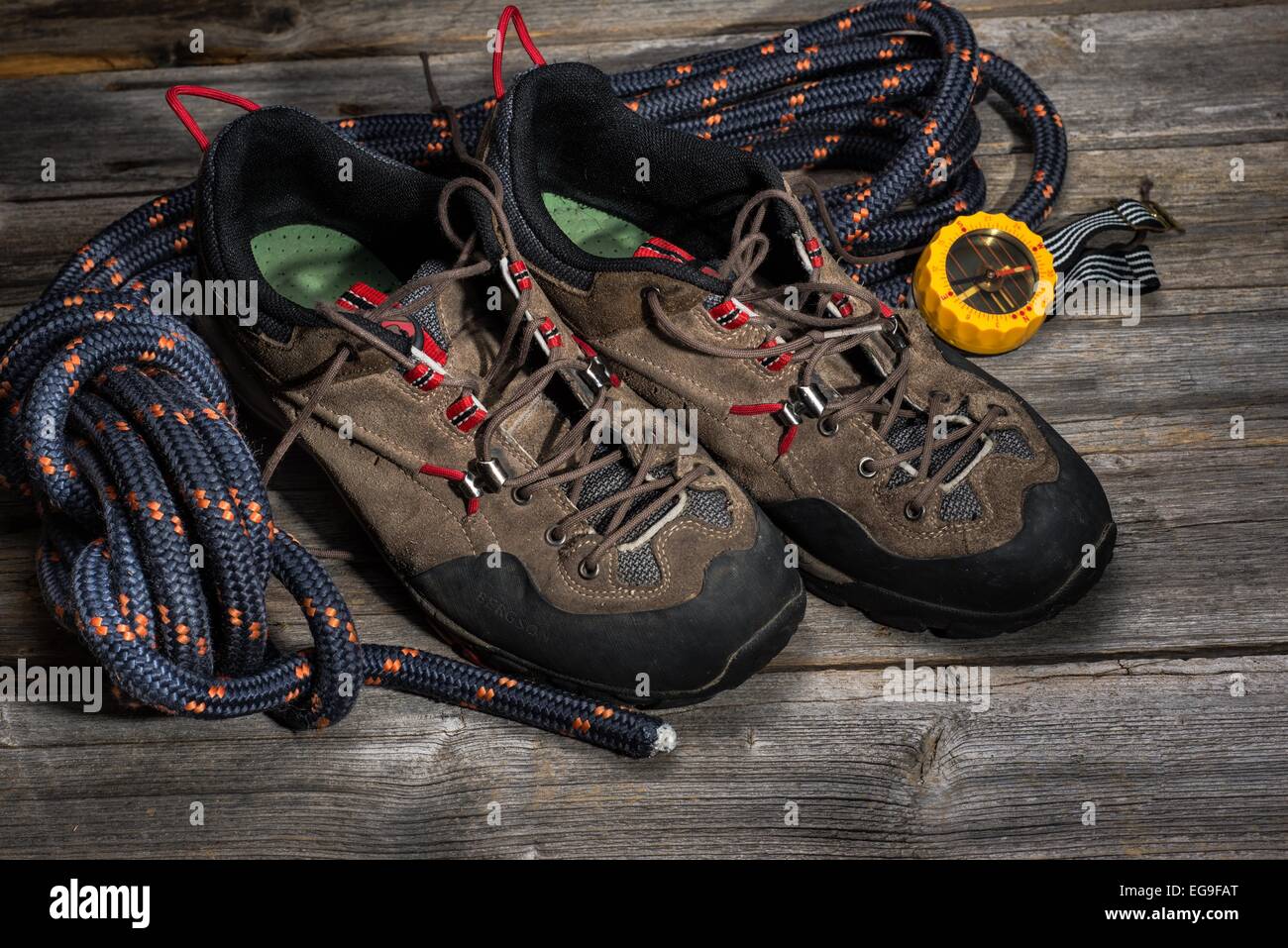 Ein trekking-Schuhe mit Seil und Kompass auf hölzernen Hintergrund Stockfoto