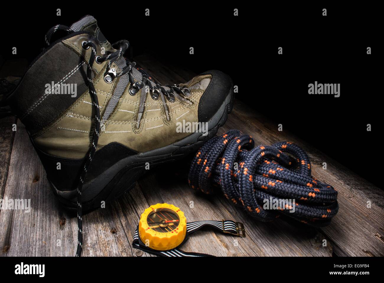 Ein Trekkingschuh mit Seil und Kompass auf hölzernen Hintergrund Stockfoto