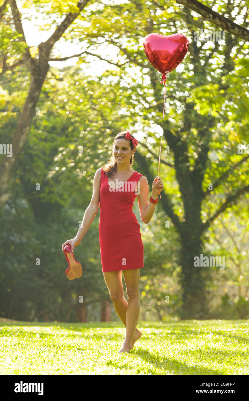 Frau mit roter Herzballon Form zu Fuß im park Stockfoto