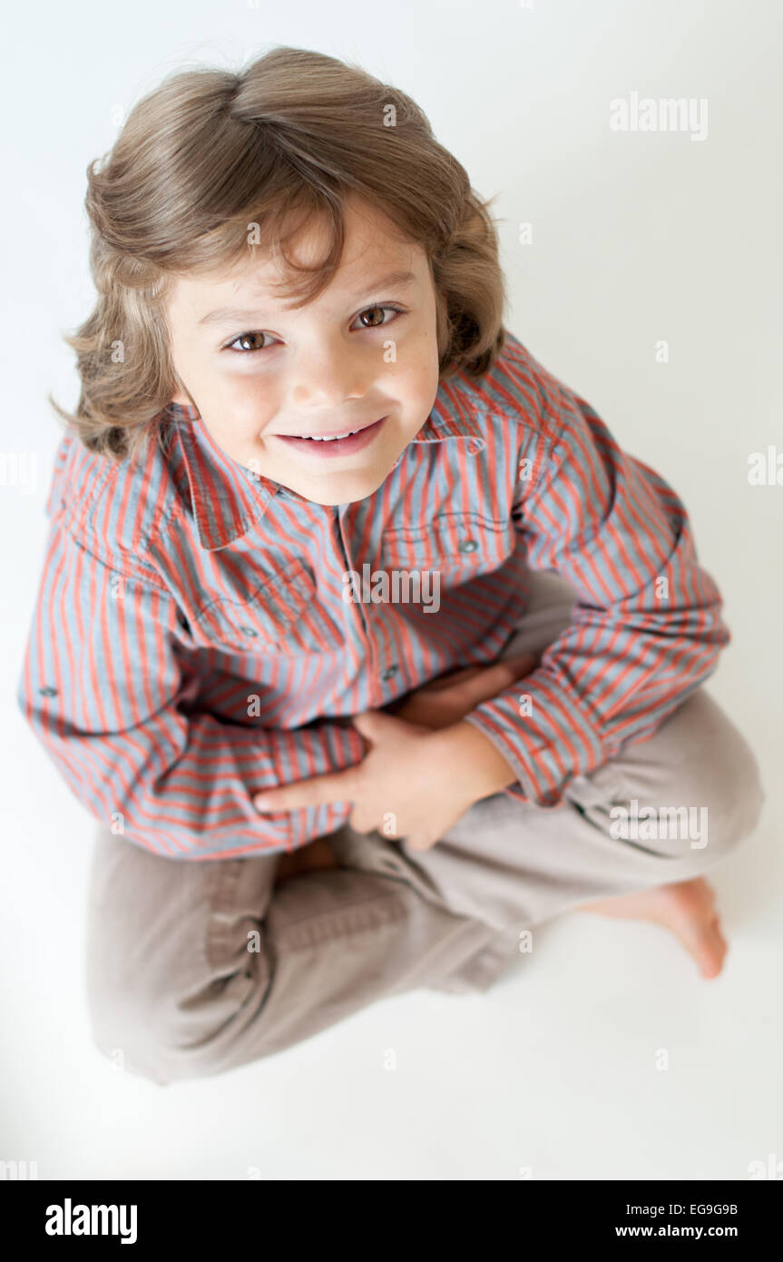 Junge nachschlagen (6-7) sitzen im Schneidersitz Stockfoto