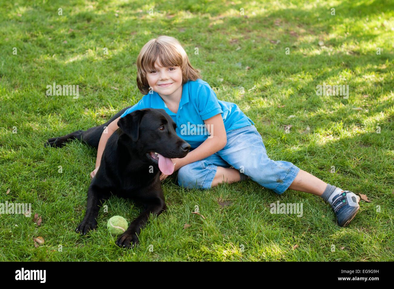 Junge (6-7) auf Rasen liegend mit Hund Stockfoto