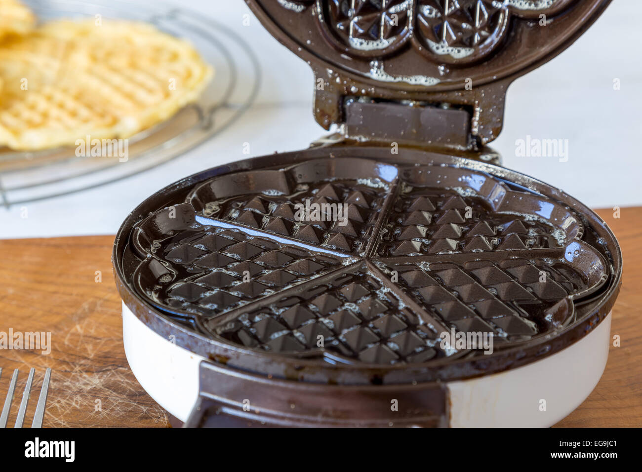 Hausgemachte Waffeln werden in einem Waffeleisen zubereitet. Stockfoto