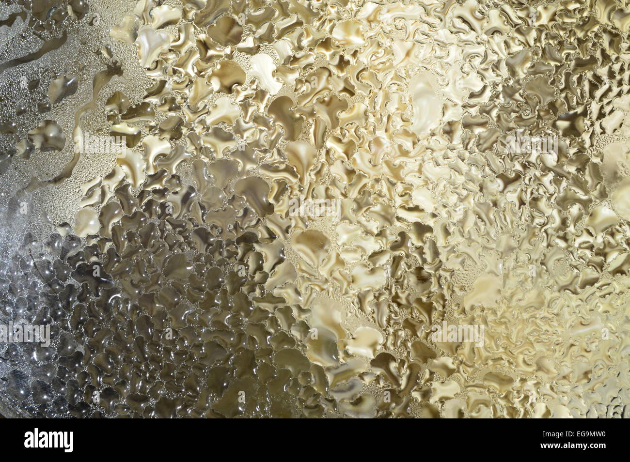 Zusammenfassung Hintergrund. Goldene Tropfen Wasser auf das Glasmaterial. Stockfoto
