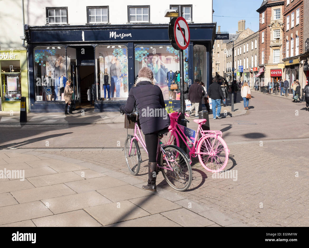 Dame auf rosa Fahrrad Werbeschild auf geparkten rosa Fahrrad Sidney Street Market Hill Kreuzung Cambridge betrachten Stockfoto