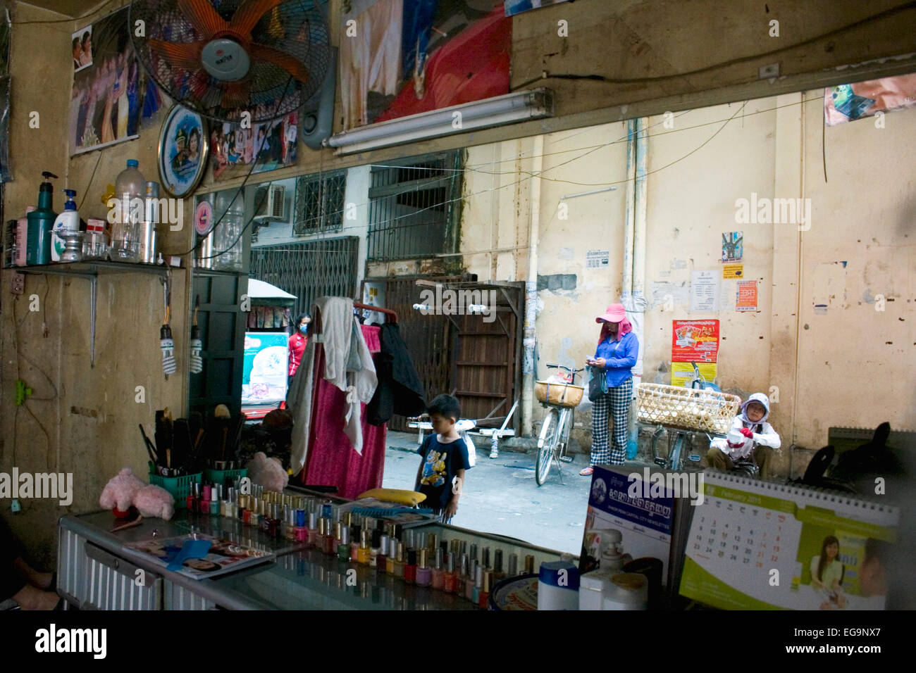 Ein Spiegel in einem Schönheitssalon reflektiert Streetfood Verkäufer ruht in einer Gasse in Penh, Kambodscha. Stockfoto