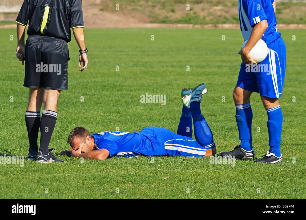 Schiedsrichter und zwei Fußballspieler und-Trainer Stockfoto