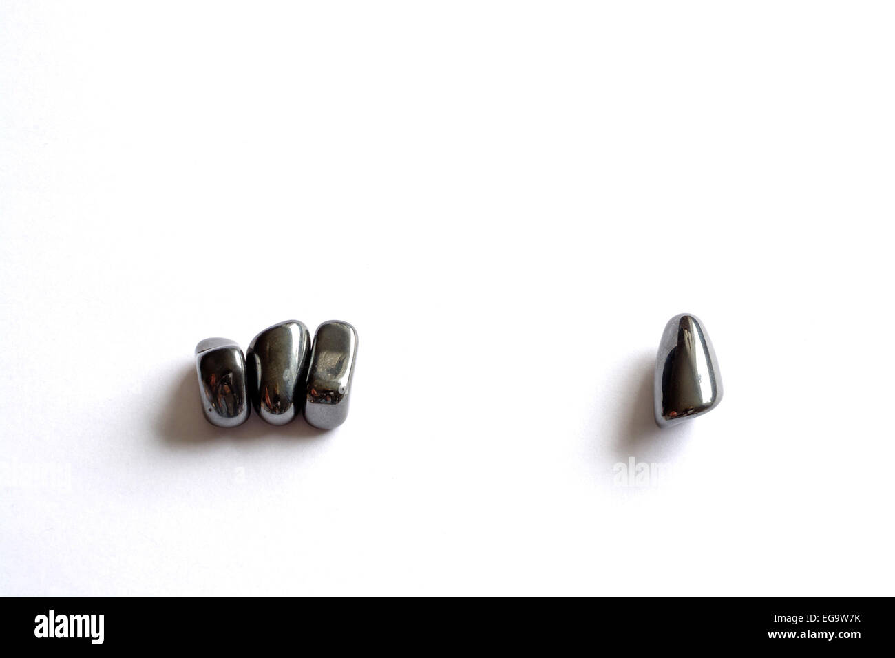Magnetit-Steinen, drei beisammen sitzen und eine ist getrennt. Spannung. Stockfoto