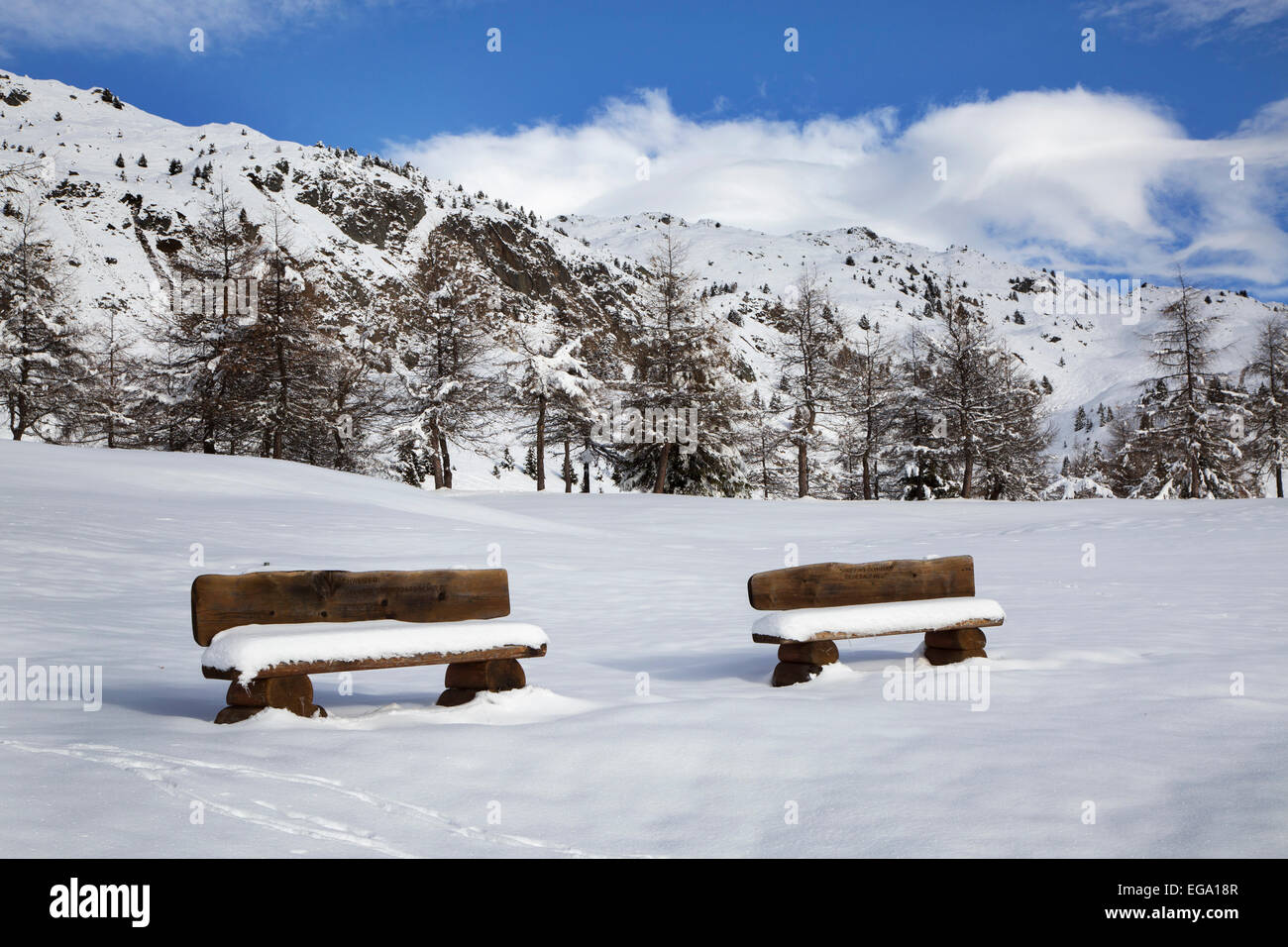 Zwei schneebedeckte Holzbänke im Dorf Riederalp im Winter, Wallis / Valais, Schweiz Stockfoto