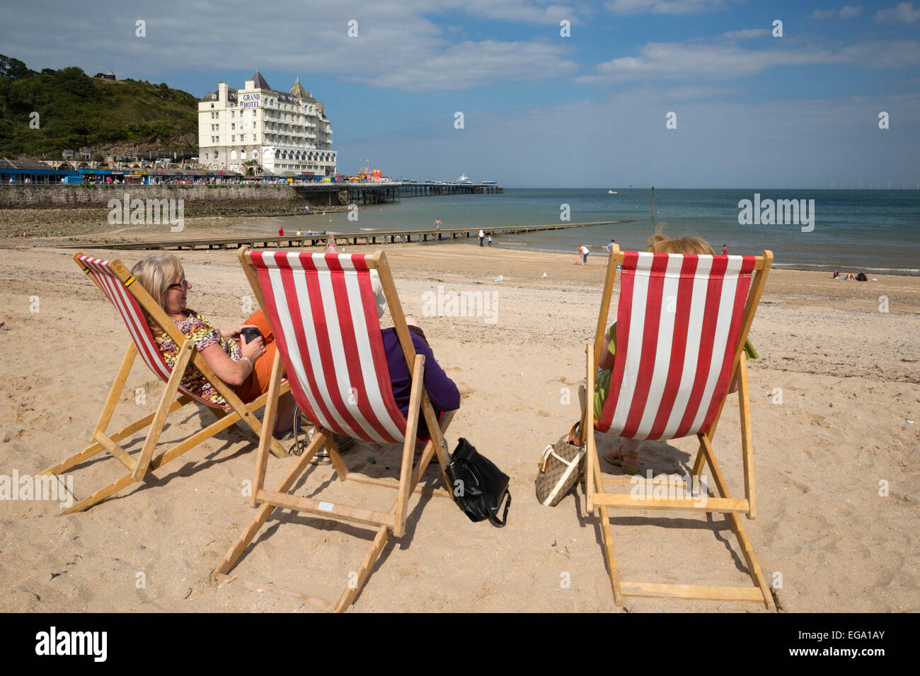 Liegestühle am Strand mit dem Grand Hotel, Llandudno, Conwy, Wales, Vereinigtes Königreich, Europa Stockfoto