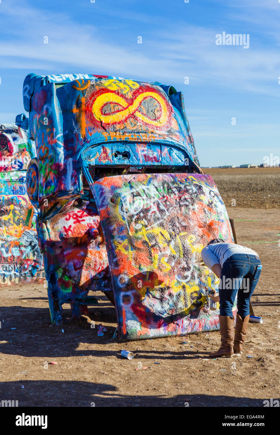 Junge Frau Spritzlackierung ein Auto auf der Cadillac Ranch, eine Kunst im öffentlichen Raum-Installation den Toren Amarillo, Texas, USA Stockfoto