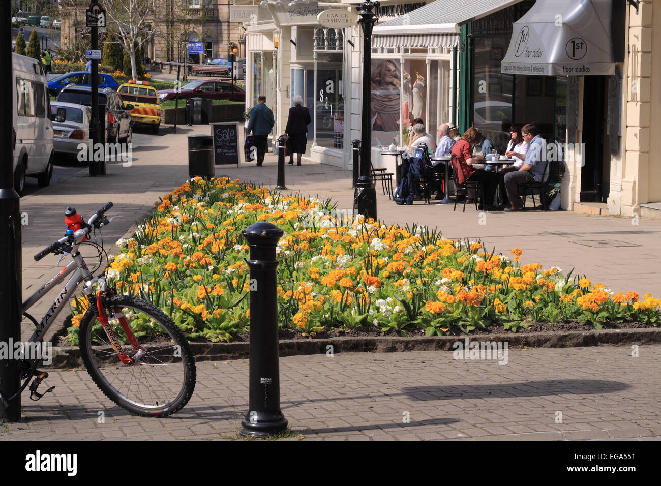 Montpelier Parade in der Sonne mit Frühlingsblumen, Fahrrad und Bürgersteig Tische vor einem Café / Harrogate / UK Stockfoto
