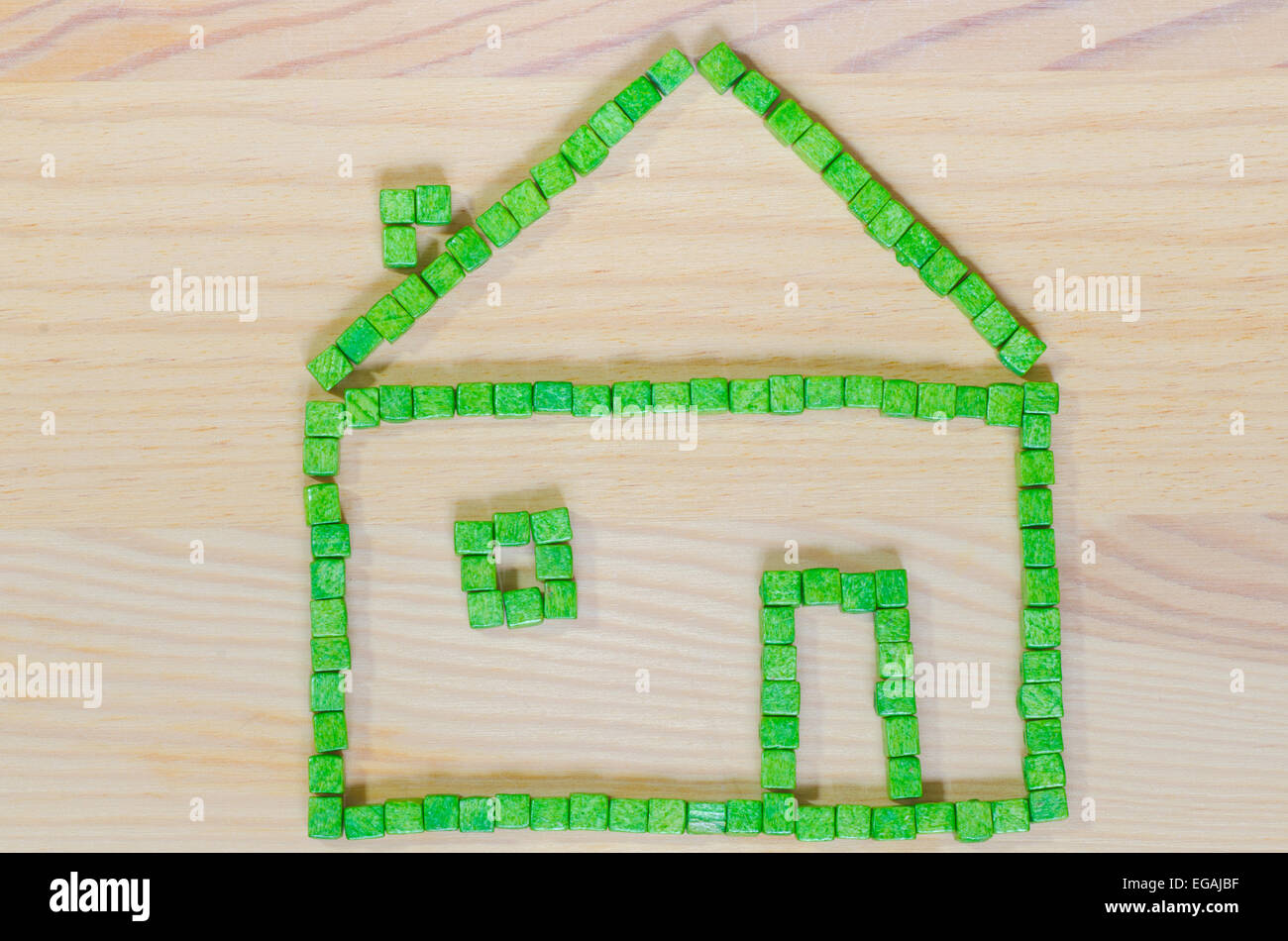 grünes Haus mit Klötzchen auf hölzernen Hintergrund gemacht Stockfoto