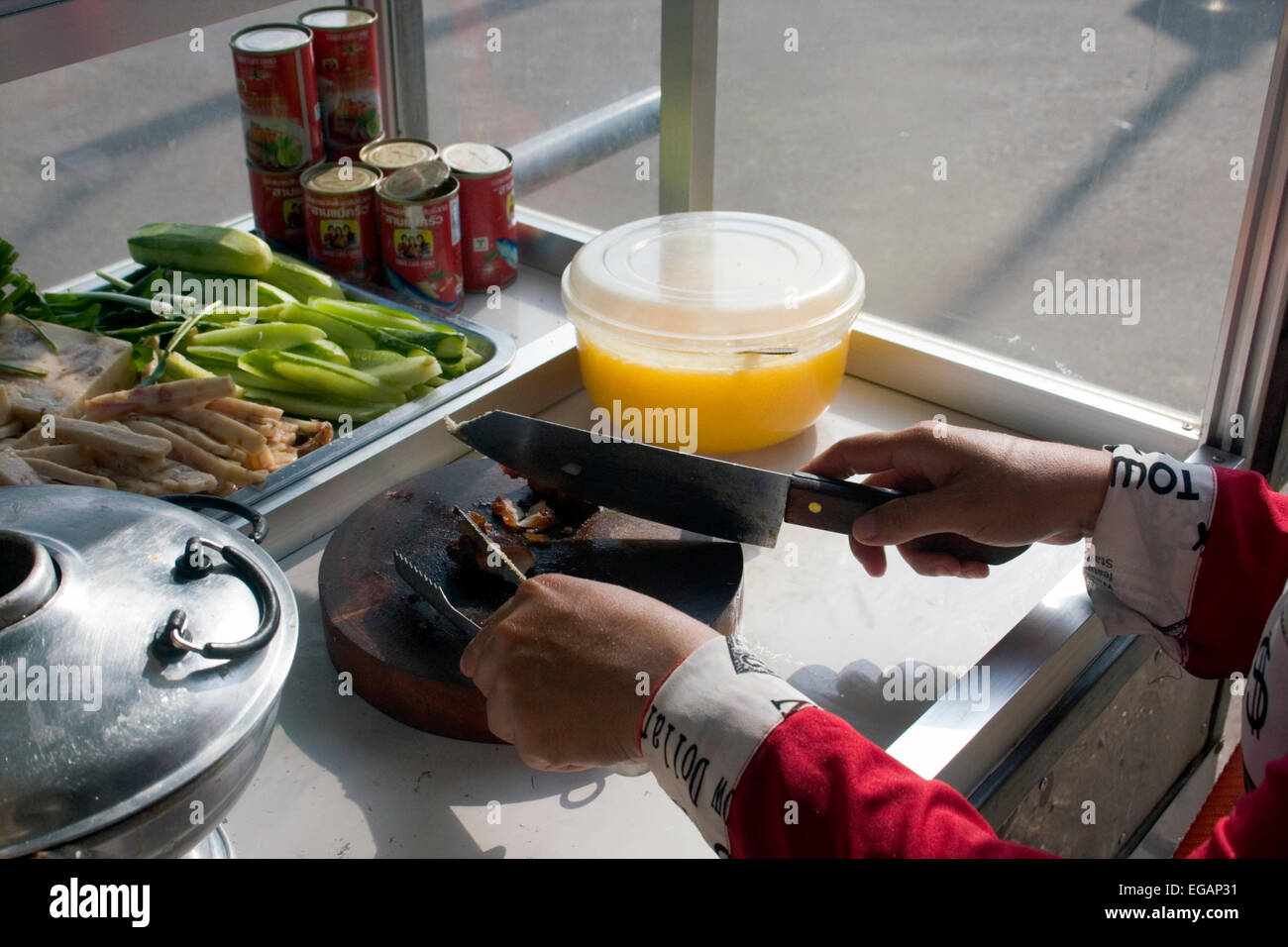 Eine Frau sind, Schneiden von Fleisch mit einem Messer bevor Sandwiches wie sie Essen auf eine Stadt in Kampong Cham, Kambodscha Straße verkauft. Stockfoto