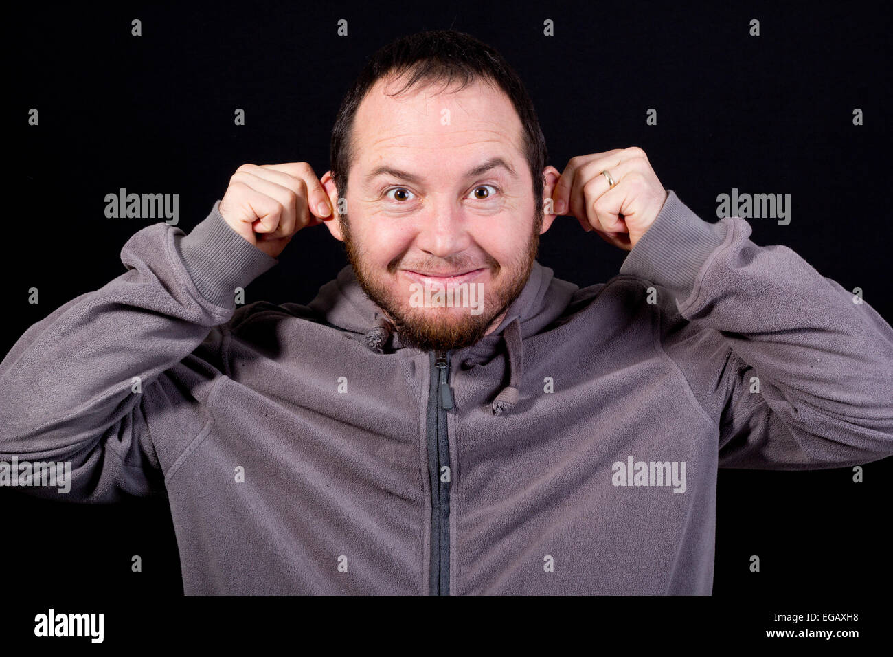 junger Mann, der ein lustiges Gesicht, isoliert auf schwarz Stockfoto