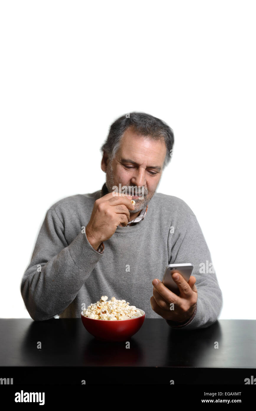 Mann mit Smartphone beim Essen Popcorn zu Hause Stockfoto