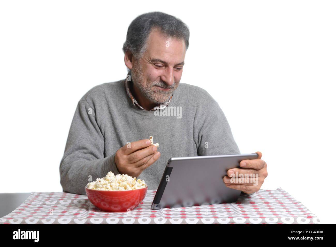 Mann mittleren Alters mit einem Tablet-Computer beim Essen Popcorn zu Hause Stockfoto