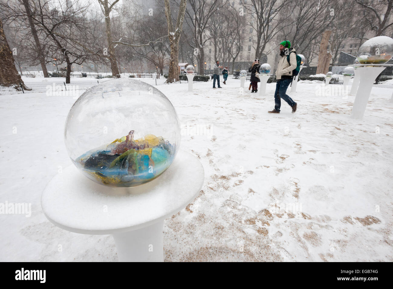 Besucher zum Madison Square Park in New York anzeigen "Gazing Globes" des Künstlers Paula Hayes im Schnee auf Samstag, 21. Februar 2015.  Die Globen erinnert an reverse Schneekugeln mit dem Schnee draußen, sind Terrarien mit Resten der Gegenwartskultur, Fundstücke, darunter Cast of Technology mit pflanzlichen Stoffen und Kristallen gefüllt. Ein schnell bewegendes Wintersturm trifft New York Hinterlegung bis zu vier Zoll Schnee, für die bereits bestehenden Schutthalden schmutzig Eis. (© Richard B. Levine) Stockfoto