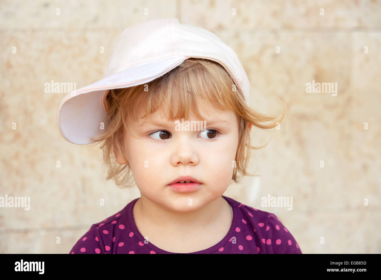 Outdoor Closeup Portrait von neugierig niedliche kaukasischen blonde Baby Mädchen in Baseball-cap Stockfoto