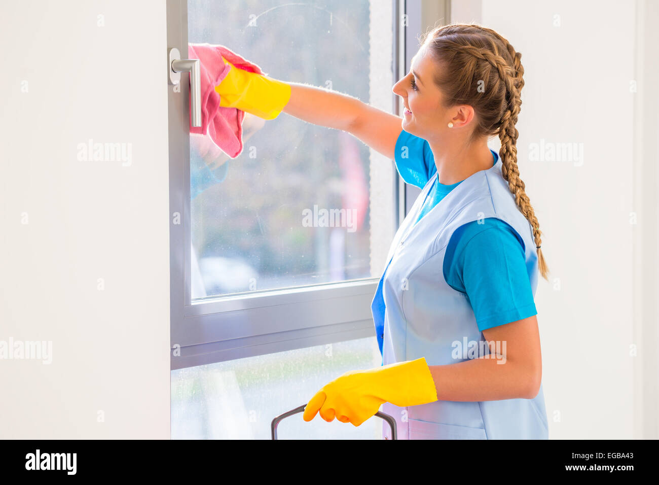 Putzfrau mit Tuch am Fenster Stockfoto