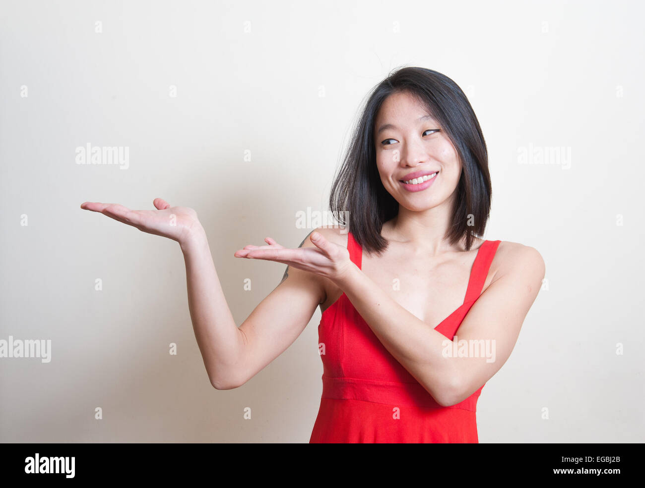 Junge schöne asiatische Frau im roten Kleid Lächeln und den Hinweis auf weißem Hintergrund Stockfoto